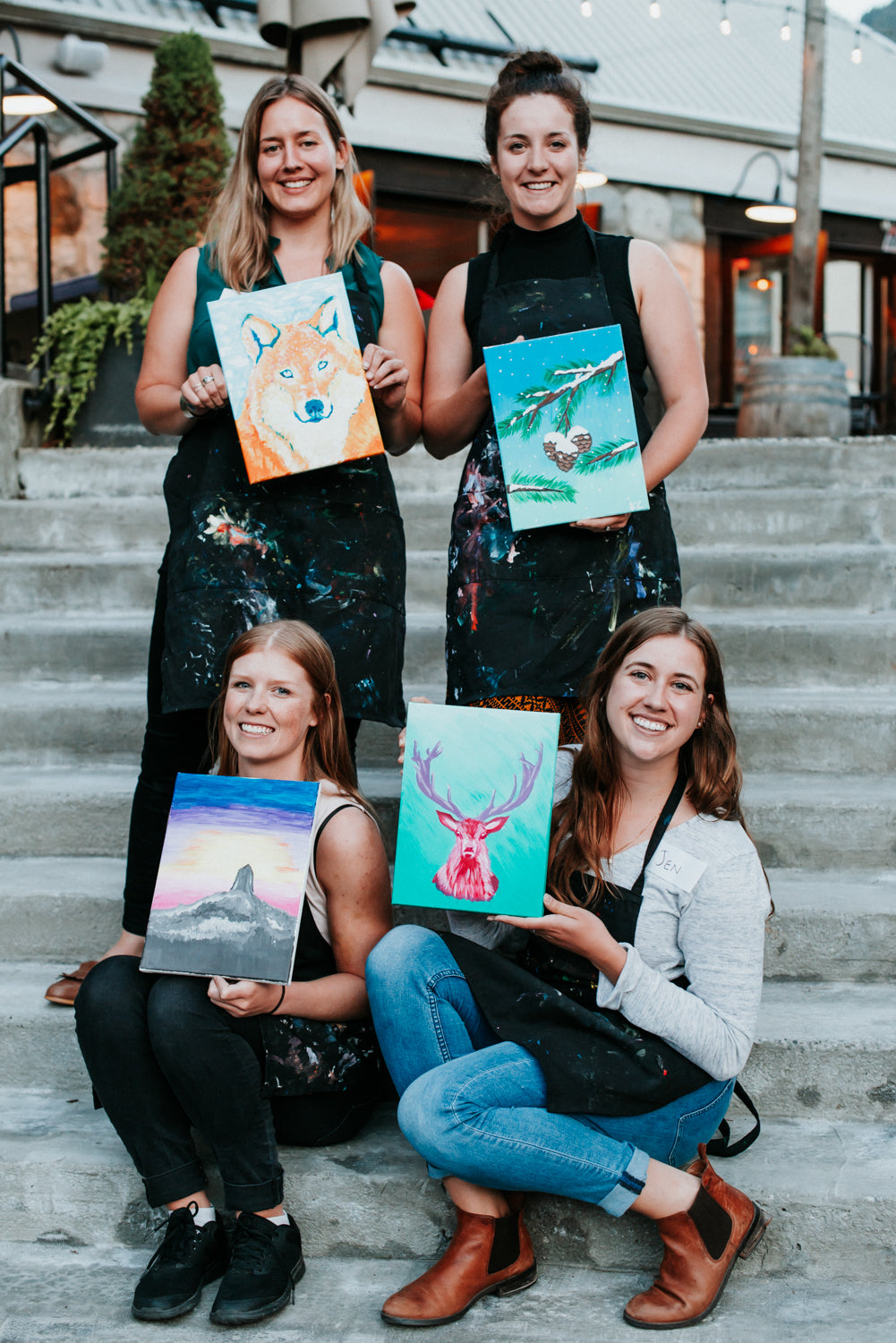 Ladies holding finished paintings after Whistler artist Andrea Mueller's paint night