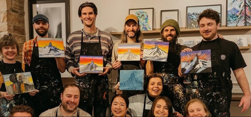 Group of people teambuilding, holding paintings of mountains and landscapes in Whistler at ART POP Studio