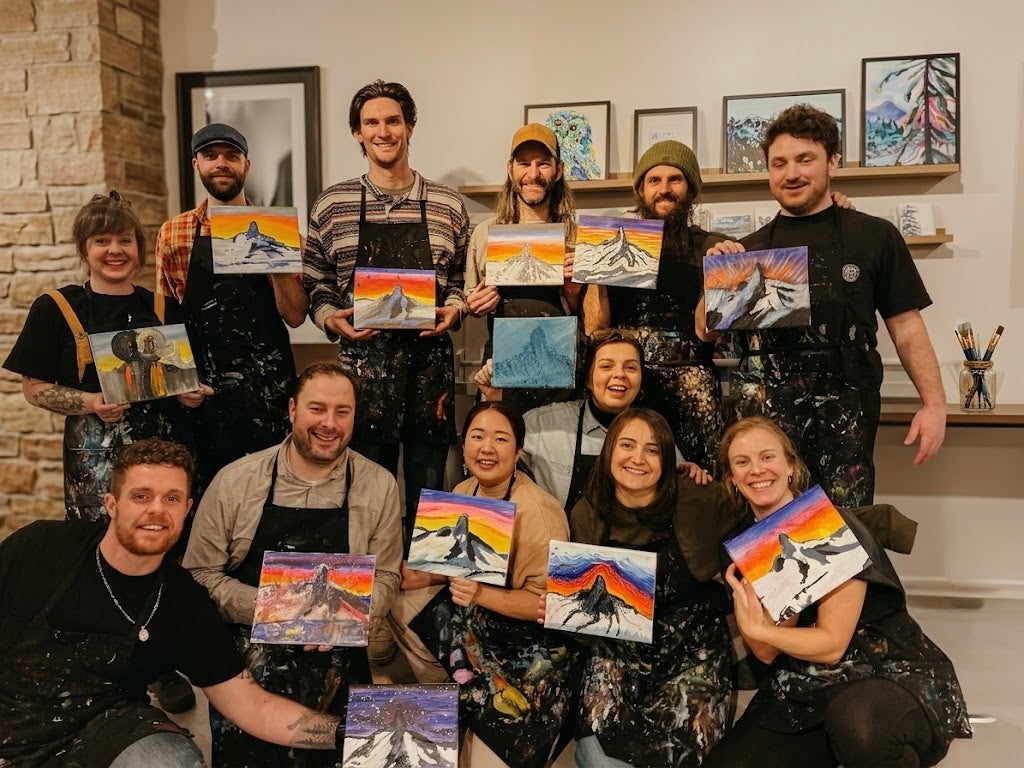 Group of people teambuilding, holding paintings of mountains and landscapes in Whistler at ART POP Studio
